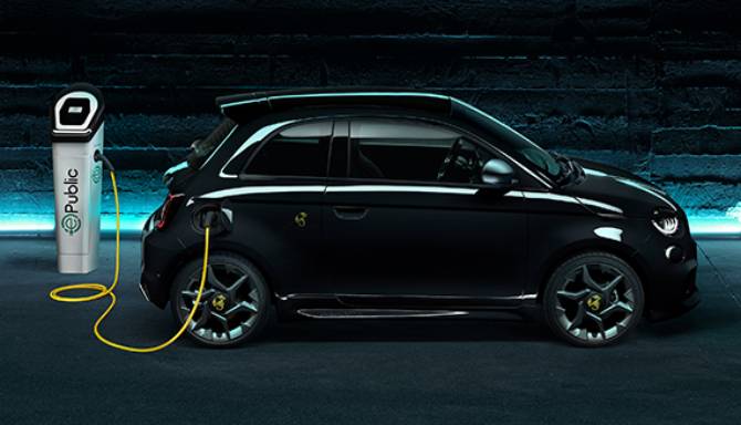 Electric car charging at a public charging station with a yellow cable.