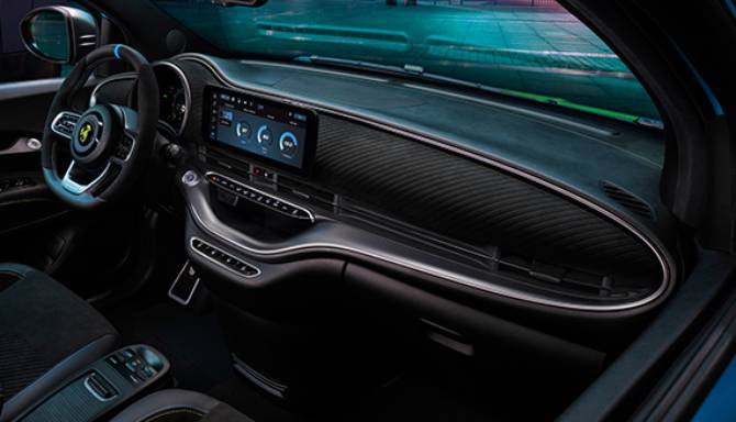 Car interior with steering wheel and touchscreen display from driver's side view.