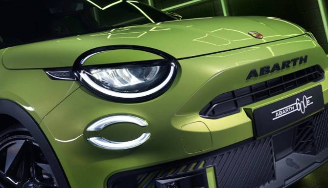 Close-up of green Abarth electric vehicle front view showcasing badge and headlight design.