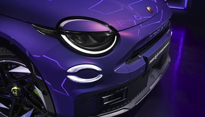 Close-up of a purple car front with illuminated round headlights.