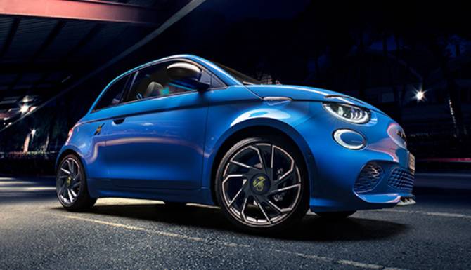 Blue compact car with alloy wheels, viewed from the front-left at night.