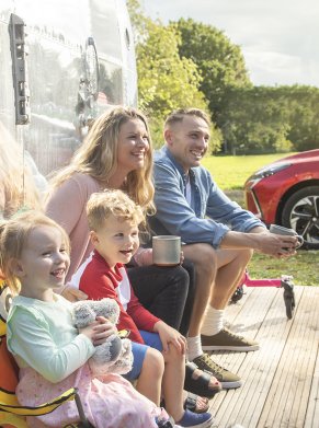 a family sat outside a caravan