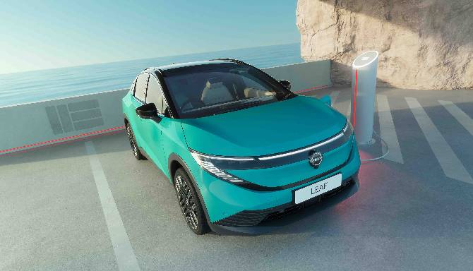 Teal electric car at charging station near a wall.