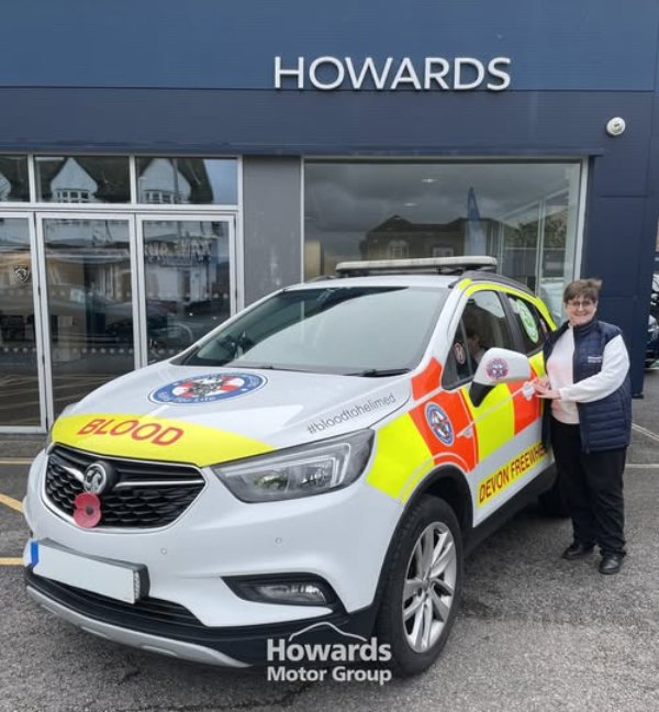 A person standing next to a Devon Freewheelers blood transport vehicle outside Howards.