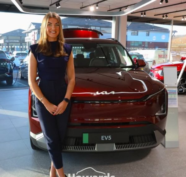 Woman standing beside a red EV5 car in a showroom.