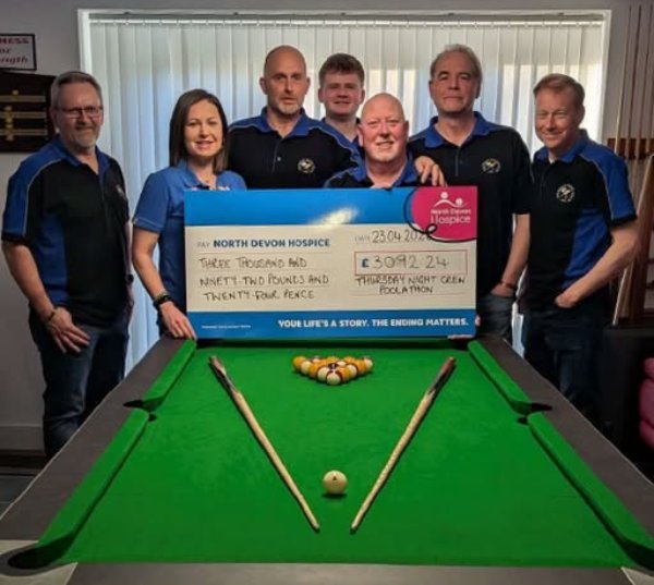 Group holding a cheque for North Devon Hospice, standing behind a snooker table.