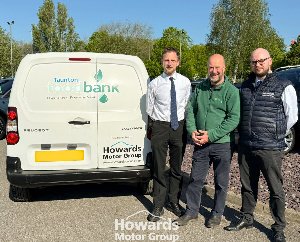 Three men stand smiling beside a Taunton food bank van.