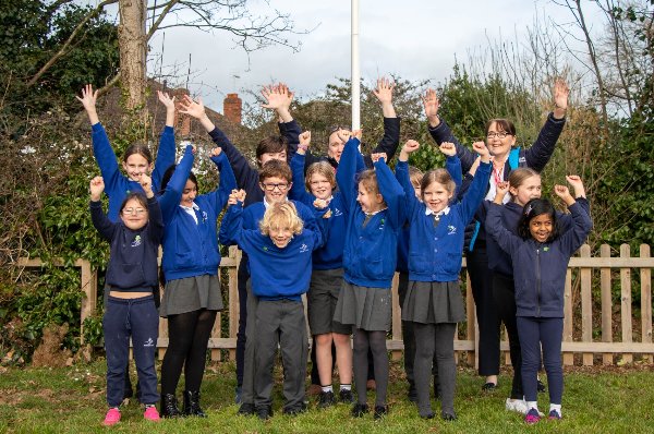 Children and adults celebrating outdoors in blue school uniforms.