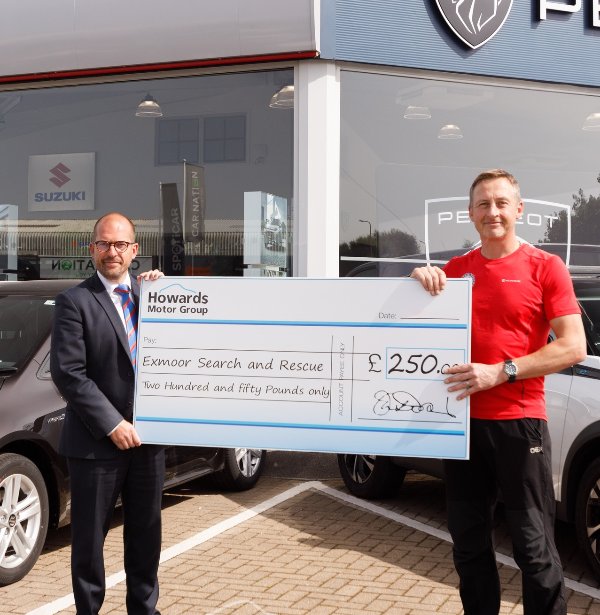 Two men holding a large cheque for £250 outside a car dealership.