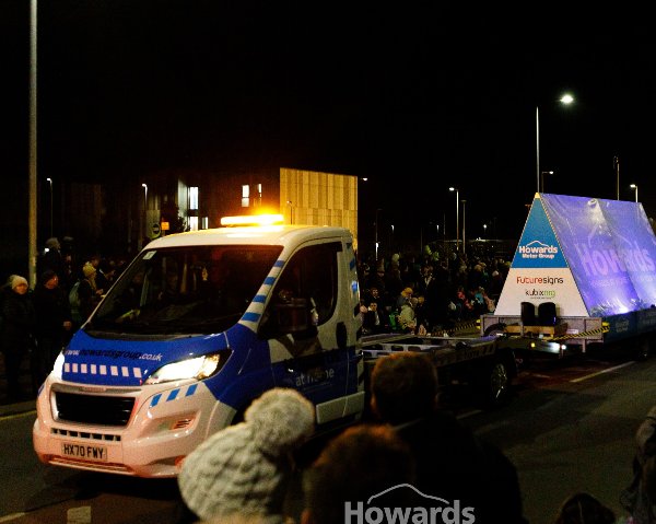A Howards Motor Group vehicle and trailer in a festive night-time parade.