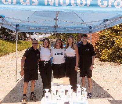 Group of five people under a promotional tent with cleaning products on a table.