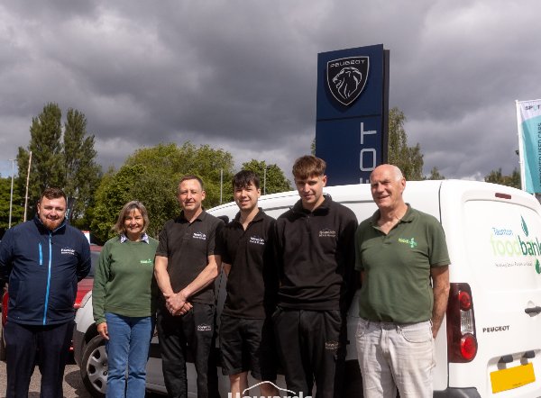 Group of six people standing beside a van with Taunton Foodbank and Howards logos.