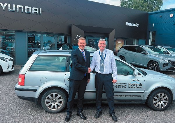Two men shaking hands in front of a car at a Hyundai dealership.