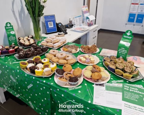 Table with assorted cakes and pastries for a Macmillan Cancer Support event.