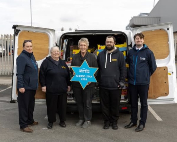 Five people stand in front of an open van holding a Shining Star 2024 sign.