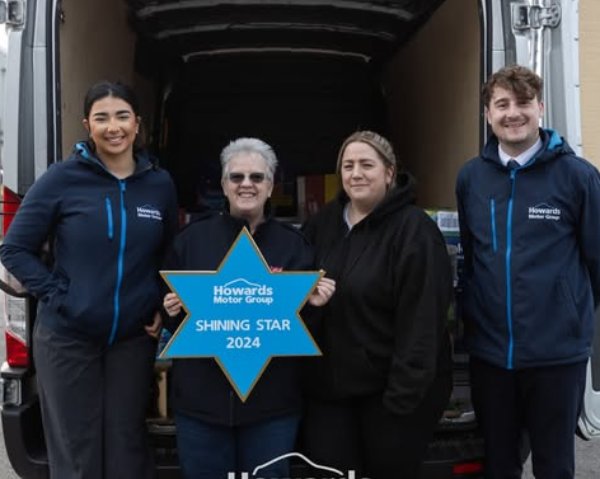 Four people standing by a van holding a Shining Star 2024 sign from Howards Motor Group.