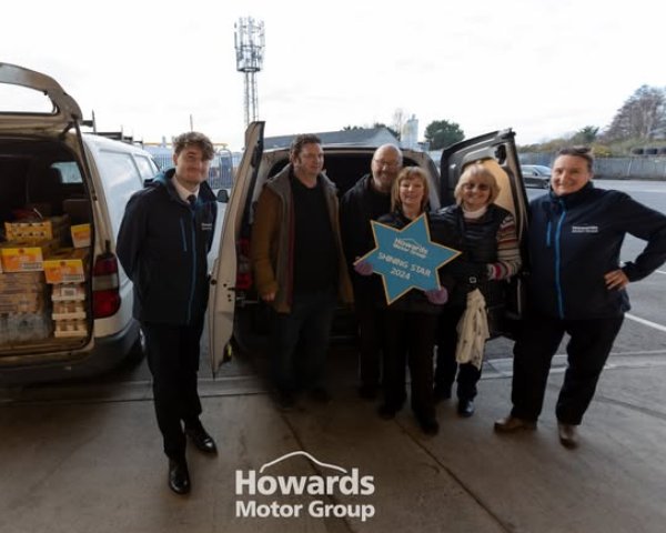 Group of six people standing between two vans, one person holding a star-shaped sign.