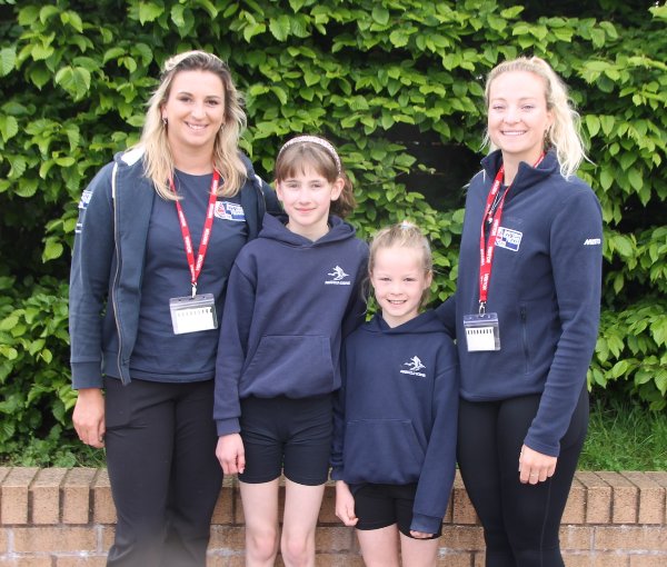 Two adults and two children in blue sportswear with ID badges, standing together.