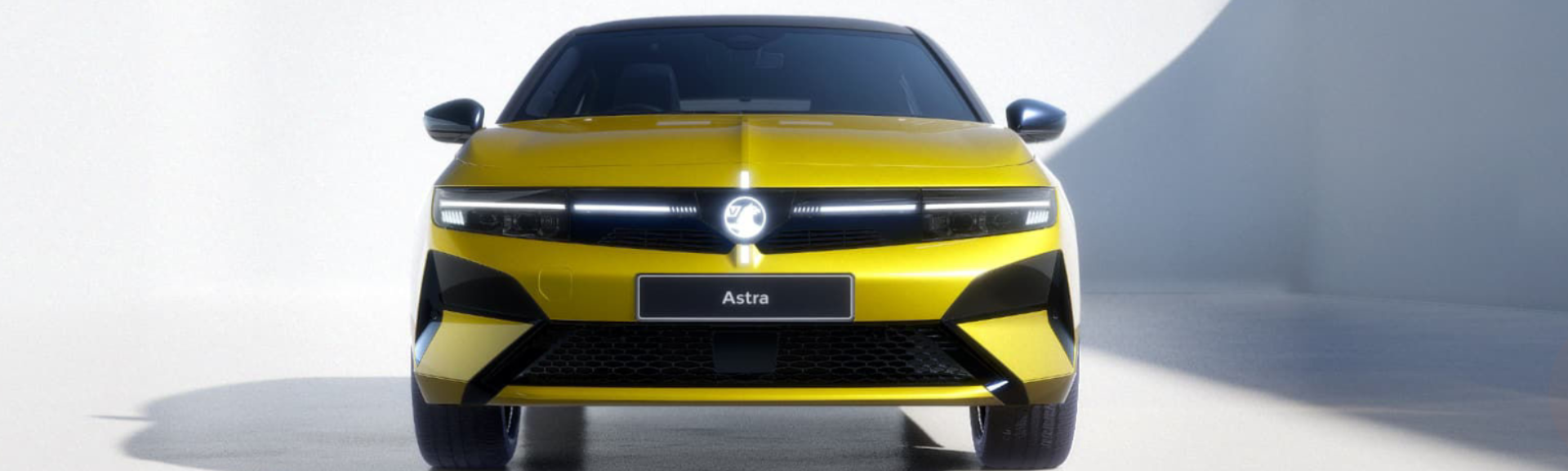 Yellow hatchback car, front view, with Astra nameplate visible.