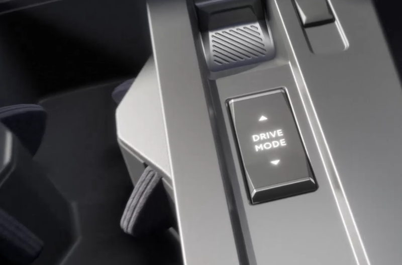 Close-up of a car's drive mode button with arrows above and below the text.