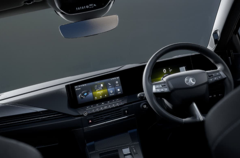 Car interior with steering wheel, digital dashboard, and touchscreen display.