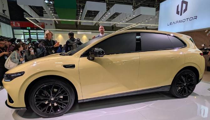 Cream SUV displayed at a car exhibition with people examining it.