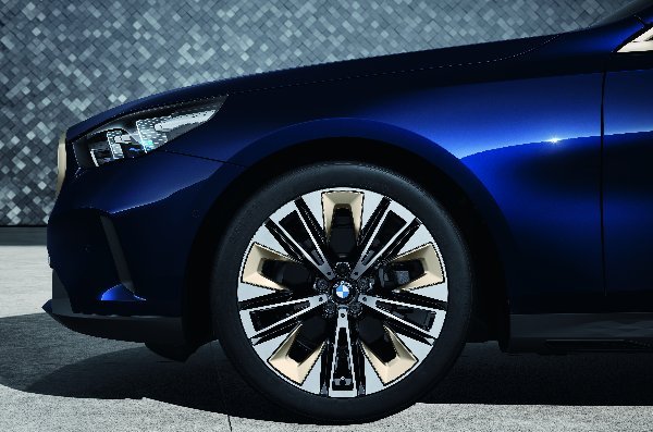 Close-up of a blue car with a detailed wheel and headlight design.