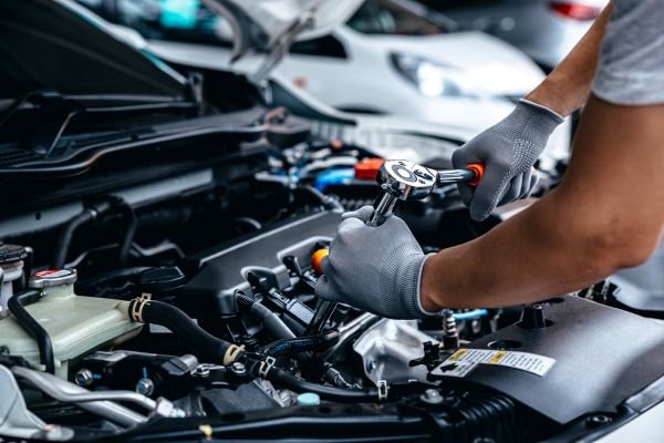 Person wearing gloves using a ratchet on a car engine.