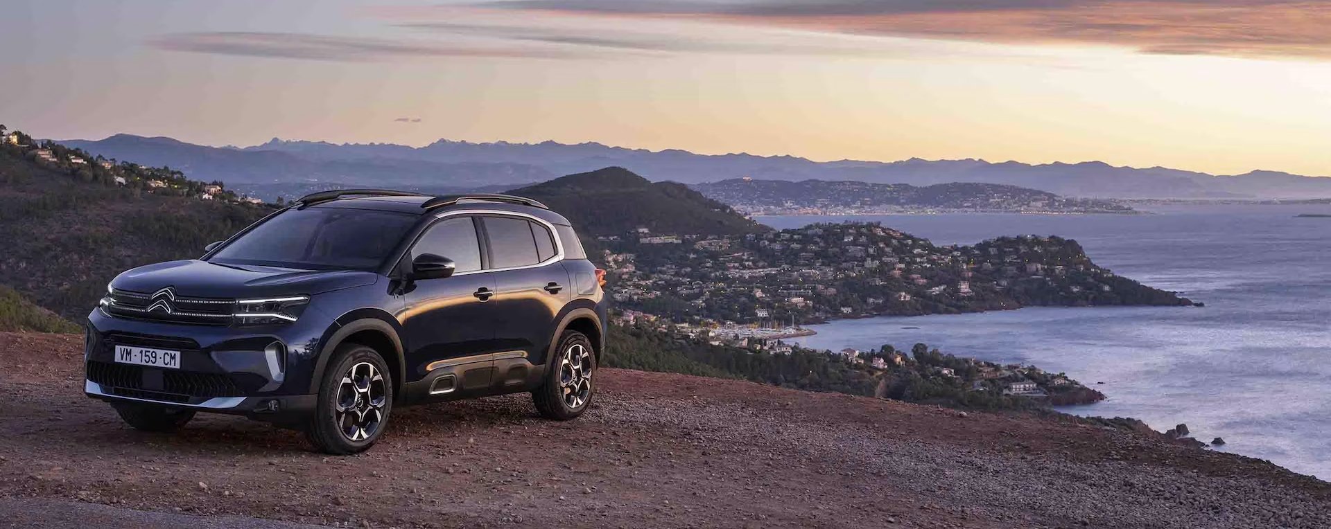 SUV parked on a hillside during sunset.