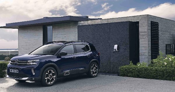 Blue SUV parked beside a building with an EV charger.