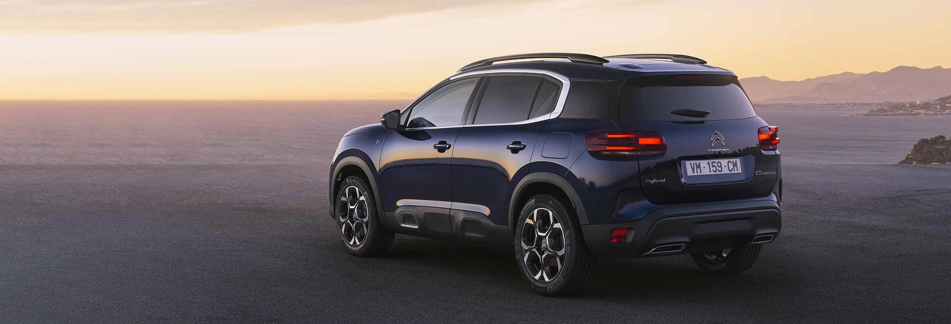 Blue SUV parked with sunset in the distance.
