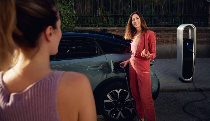 Person talking while charging an electric car at a charging station.