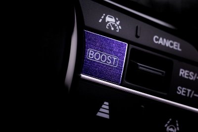 Close-up of a car steering wheel button panel with a purple BOOST button.