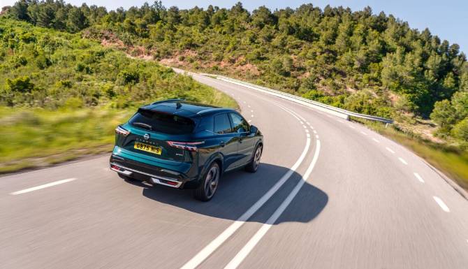 Green SUV driving on a winding road with trees alongside.
