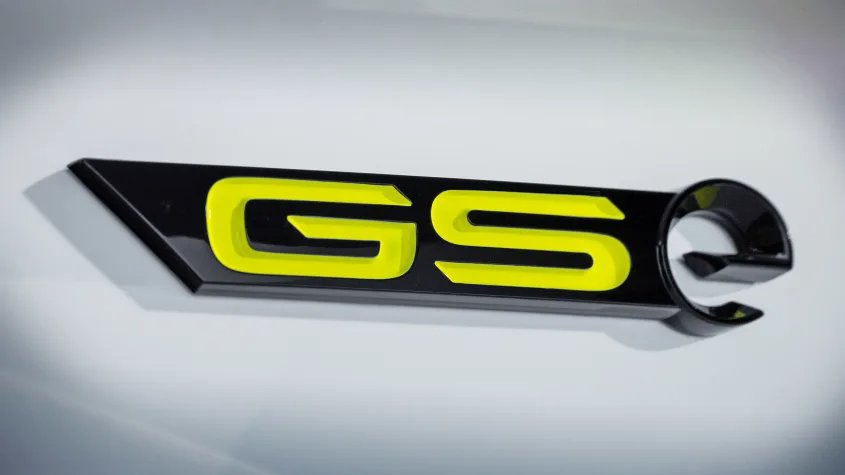 Close-up of a GS car badge with yellow lettering on a black background.