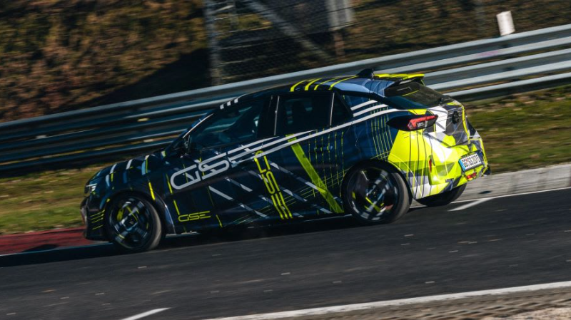 A car with a dynamic black, white, and neon yellow design on a racetrack.