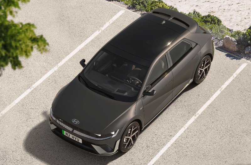 Dark grey Hyundai car parked in a space beside greenery.