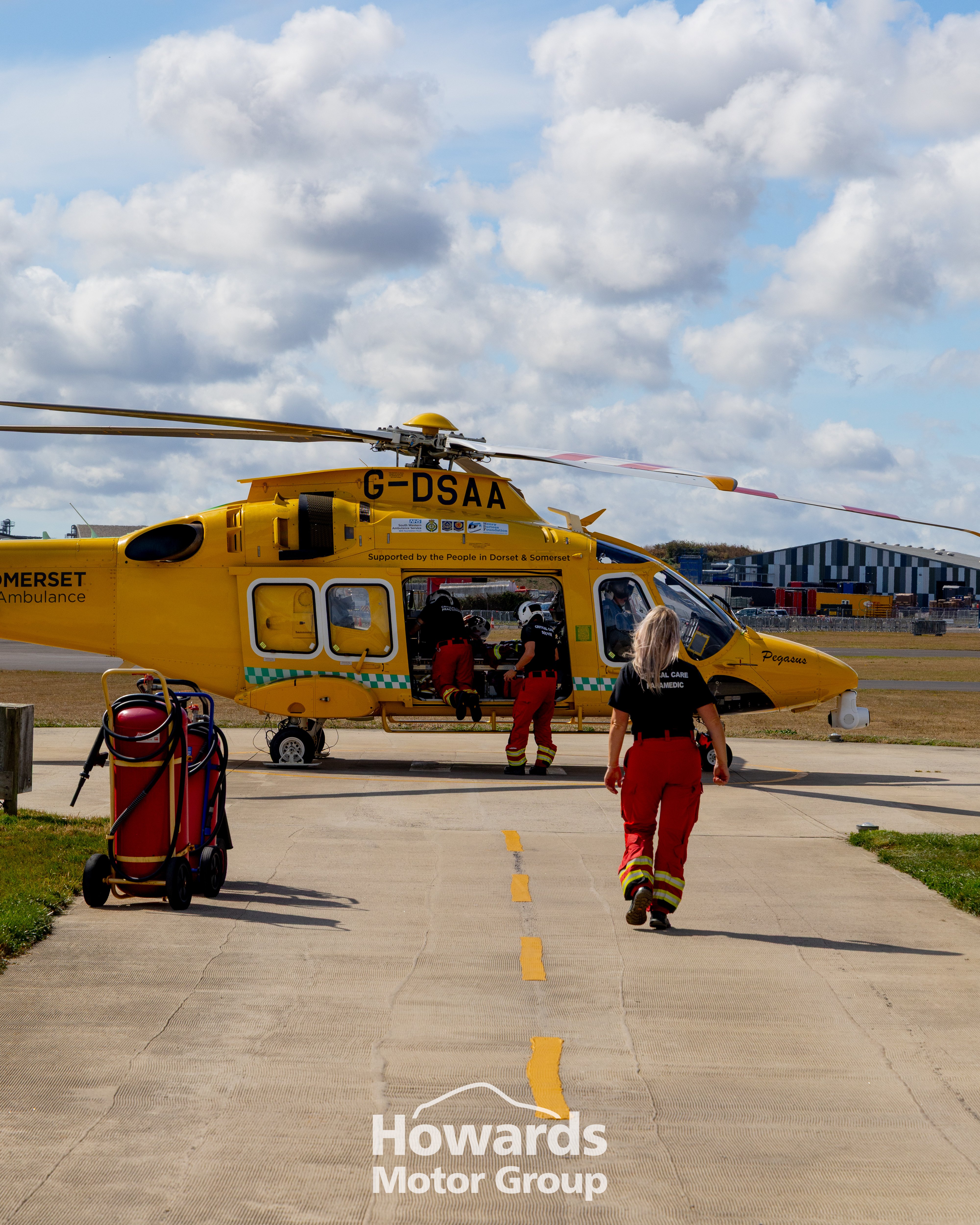 Yellow Dorset air ambulance on a runway with personnel approaching.