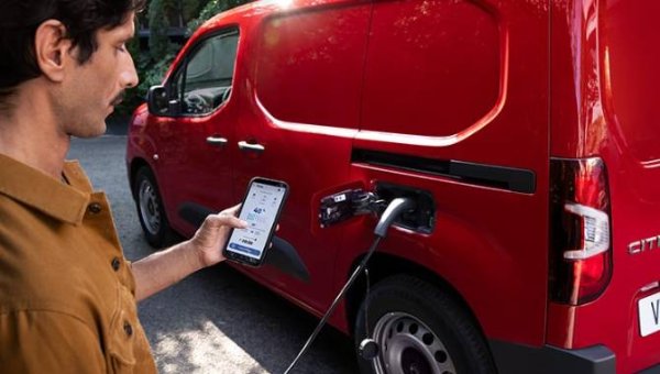 man stood next to the van charging