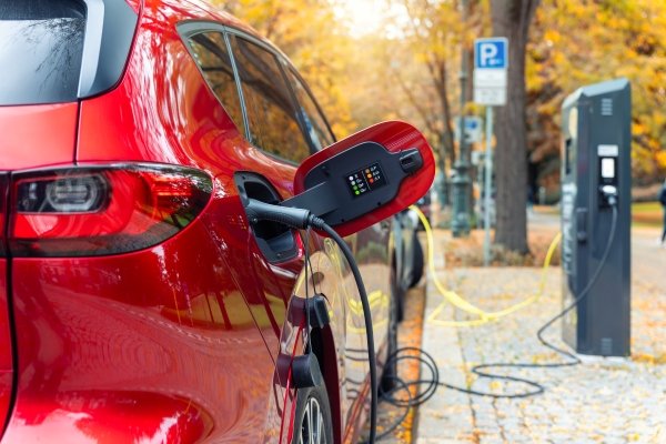 Red electric car charging at a public charging station.
