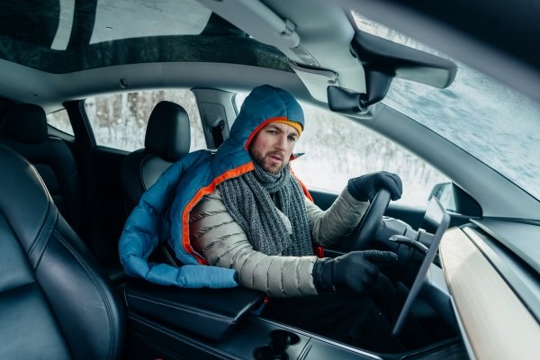 Man in winter clothes driving a car.