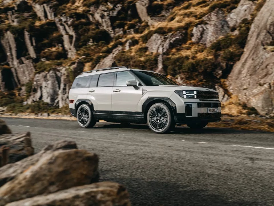 Silver SUV driving on a road with rocky terrain.