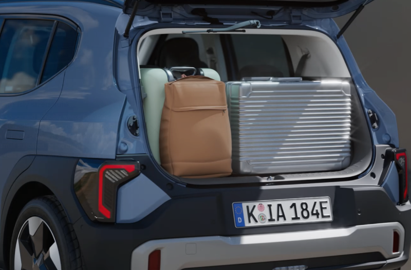 Car boot open with suitcase and brown bag inside.
