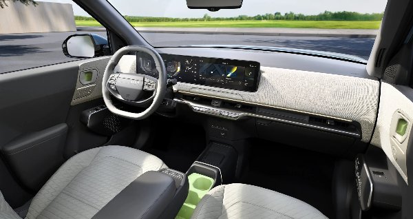Car interior showing steering wheel, dashboard, and seats with a digital display panel.