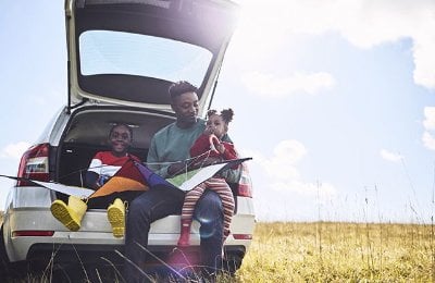Family sat on the car boot edge in a field