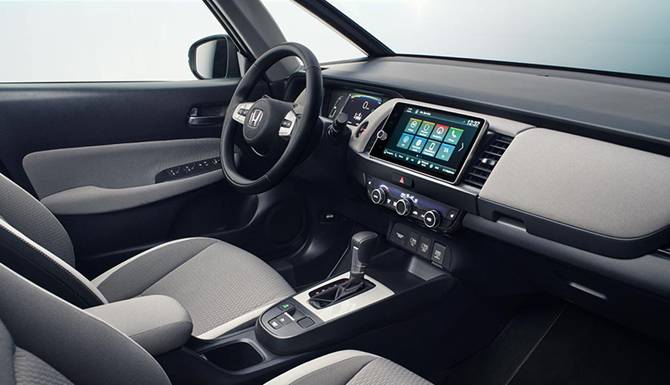 Car interior with steering wheel, touchscreen display, and automatic gear shift lever.