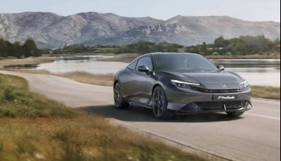 Dark grey Honda Prelude driving on a rural road with mountains in the background.