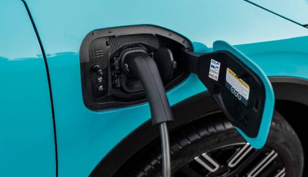 Electric vehicle charging, cable connected to a blue car's charging port.