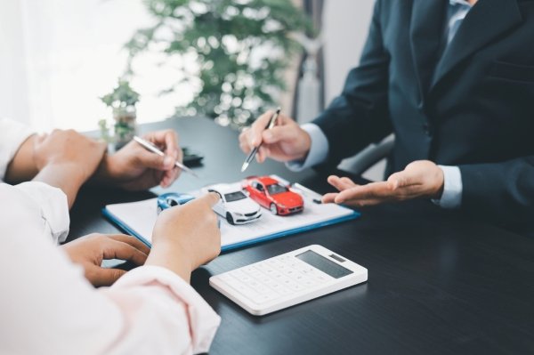 Two people discussing car model options with calculator in view.