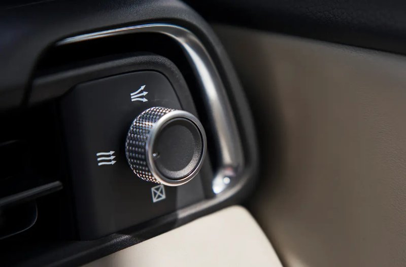 Close-up of a car's air vent control knob with directional symbols.